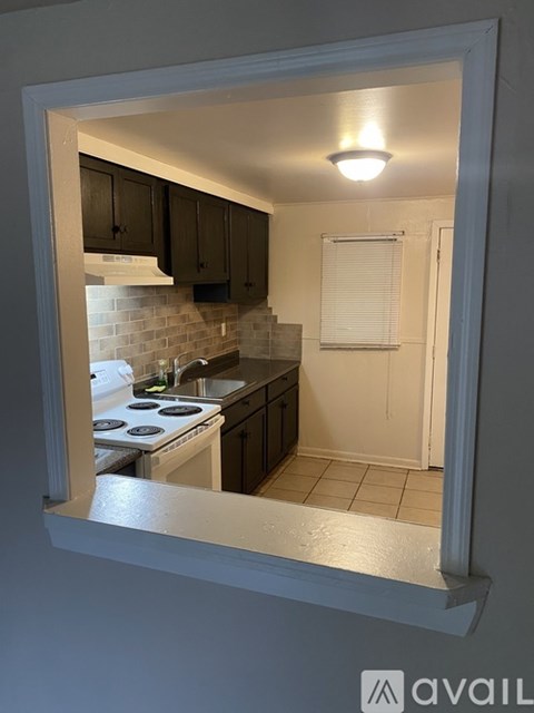 A kitchen with a stove and cabinets is visible through a window.