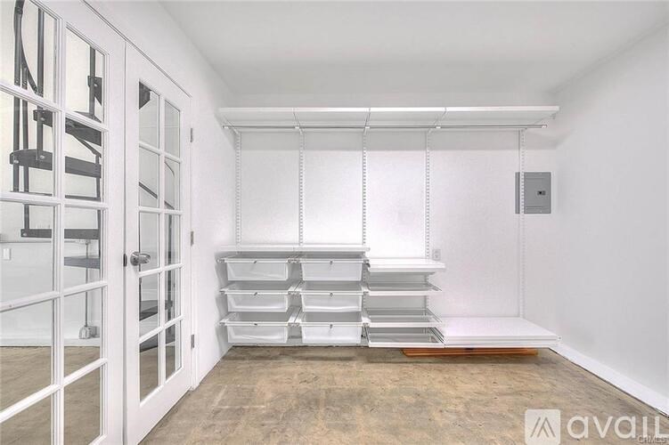 A white interior space with a staircase on the left and a set of shelves in the middle.