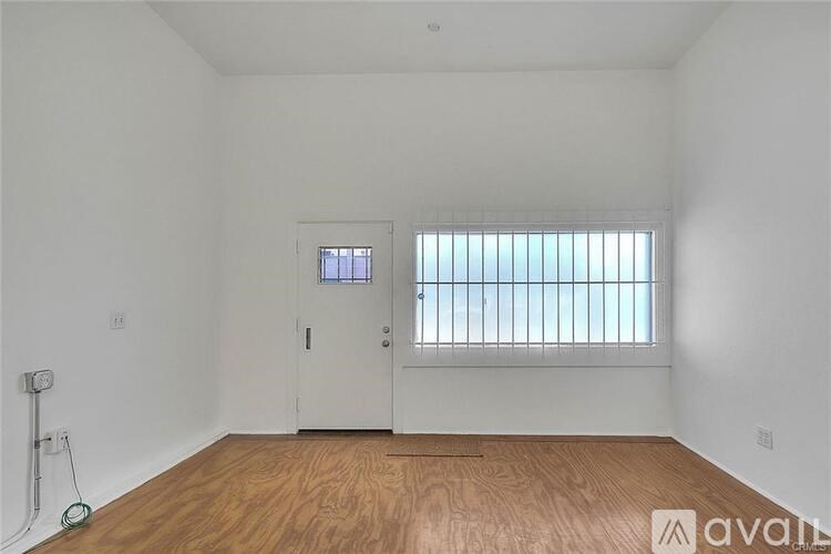 A room with wooden flooring, a door, and a window with blinds.