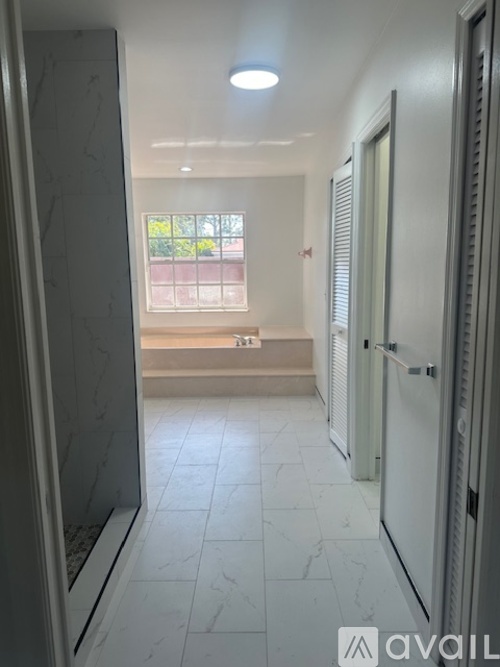 A spacious room with a ceiling fan and sliding glass doors leading to a patio.