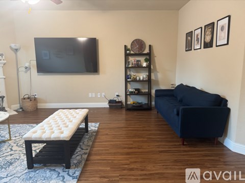 A living room with a blue couch and a television mounted on the wall.