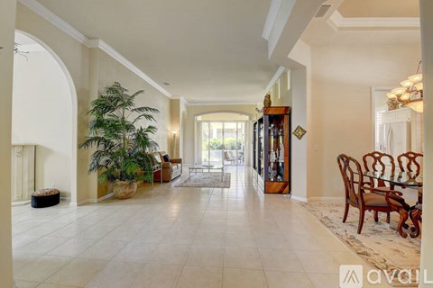 A spacious living room with a large arched doorway and a dining area with a table set for six.