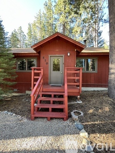 A red wooden house with a white door and windows.