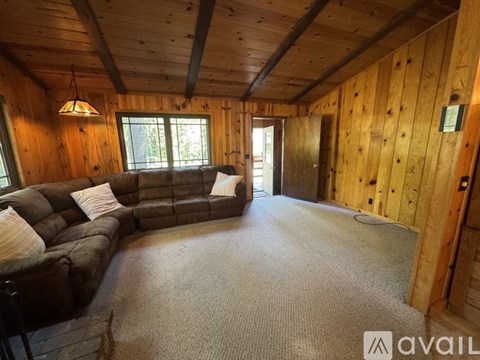 A living room with a brown leather couch and a grey carpet.