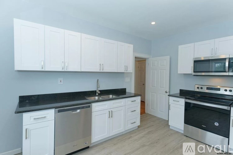 A kitchen with white cabinets and black countertops.