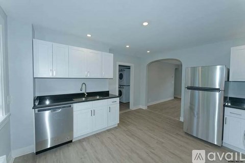 A kitchen with white cabinets and black countertops.