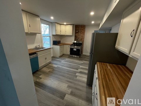 A kitchen with a wooden counter top and a brick wall.