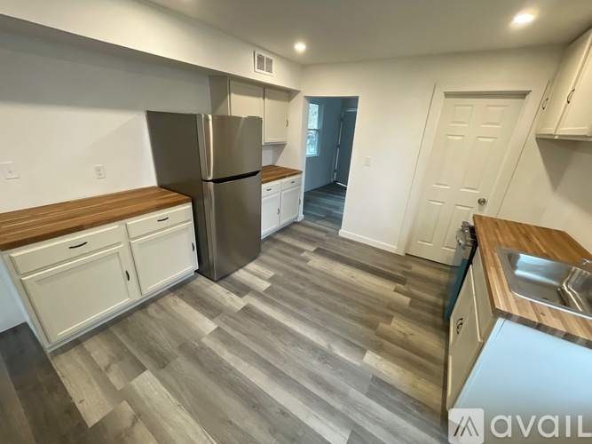 A kitchen with a refrigerator, cabinets, and a sink.