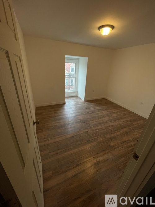 A room with wooden floors and a door on the left.