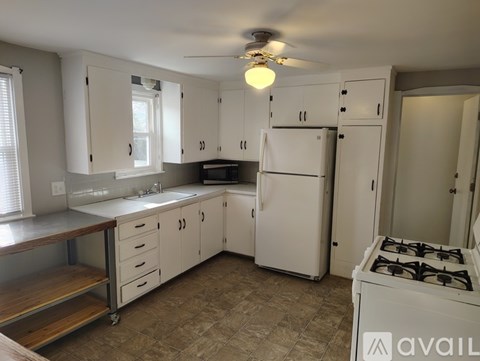A kitchen with white cabinets and a white fridge.
