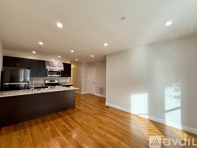 A kitchen with a refrigerator, stove, and bar stools.