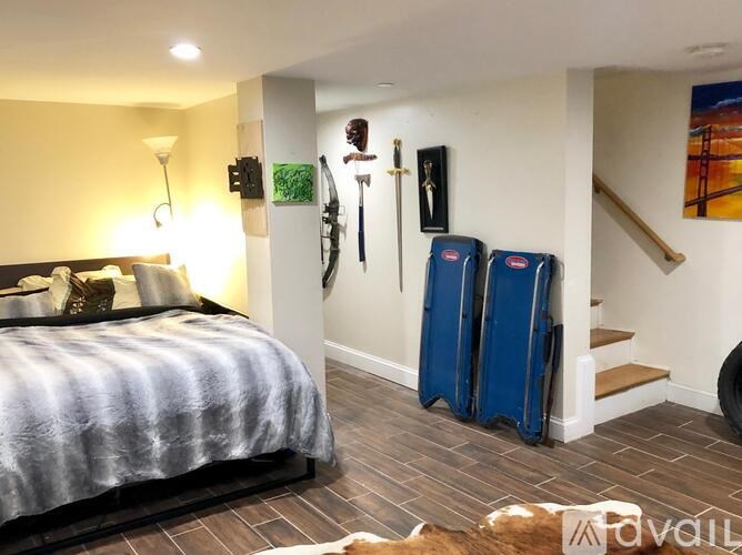 A bedroom with a bed, a staircase, and a painting on the wall.
