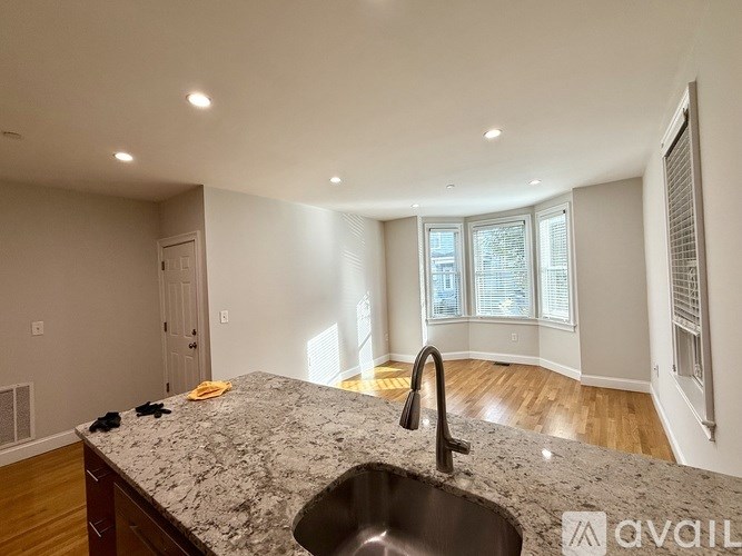 A black leather couch sits in a room with a bear head mounted on the wall.