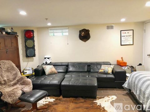 A black leather couch in a living room with a cowhide rug and a red traffic light on the wall.