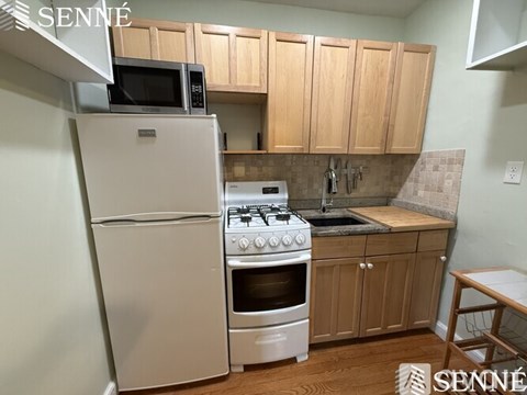 A kitchen with a white refrigerator, white oven, and white stove top.