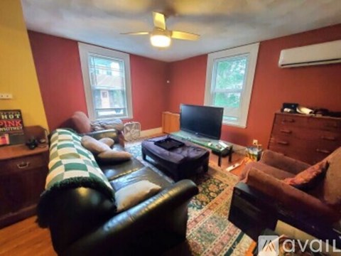A living room with a black leather couch and a television.