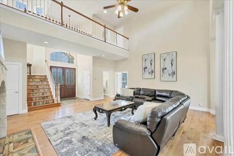 A living room with a brown leather couch and a staircase.