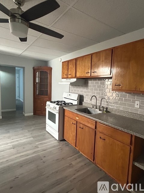 A kitchen with wooden cabinets and a white stove top oven.