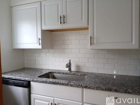 A kitchen with white cabinets and a granite countertop.