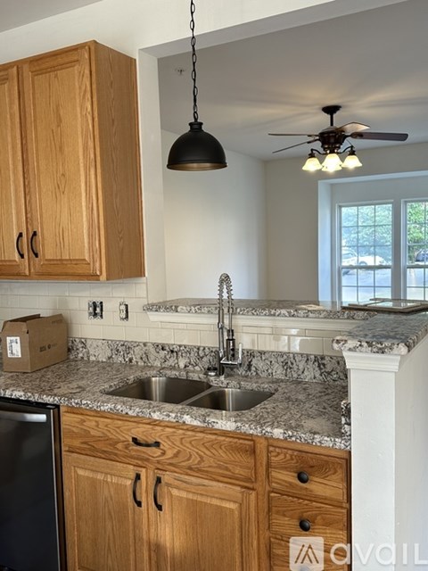 A kitchen with wooden cabinets and a black dishwasher.