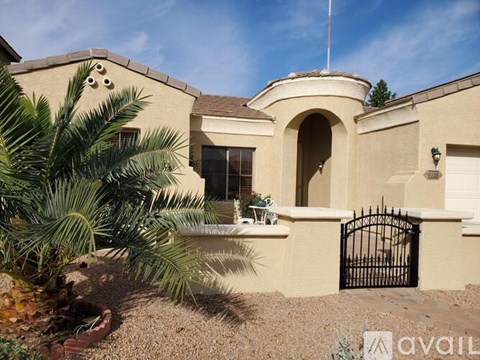 A house with a black gate and a palm tree in front.