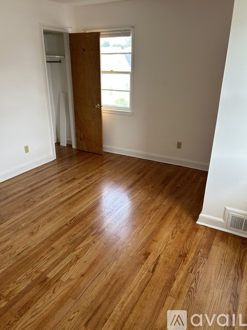 A room with wooden flooring and a door leading to another room.