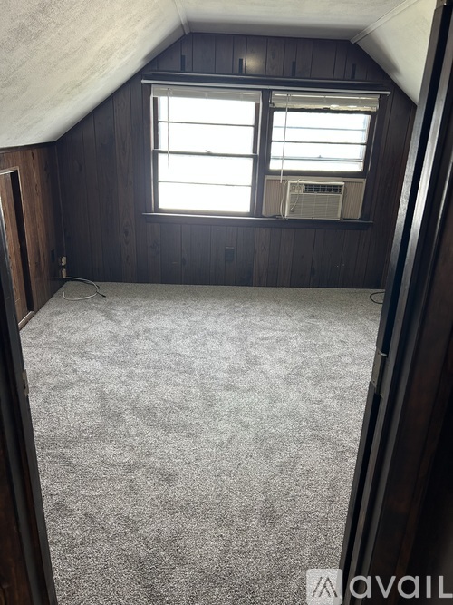 A room with a window and a carpeted floor.