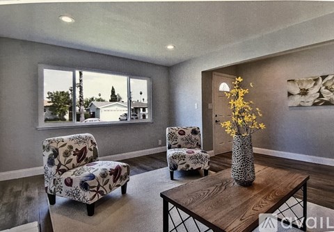 A living room with two chairs and a table with a vase of flowers on it.