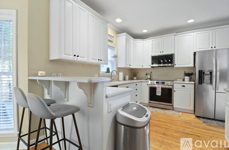 A kitchen with white cabinets and a wooden floor.
