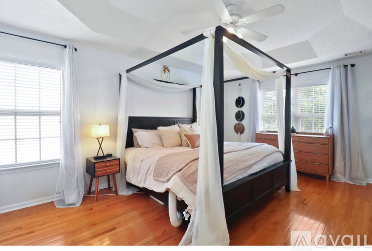 A bedroom with a canopy bed and a wooden floor.