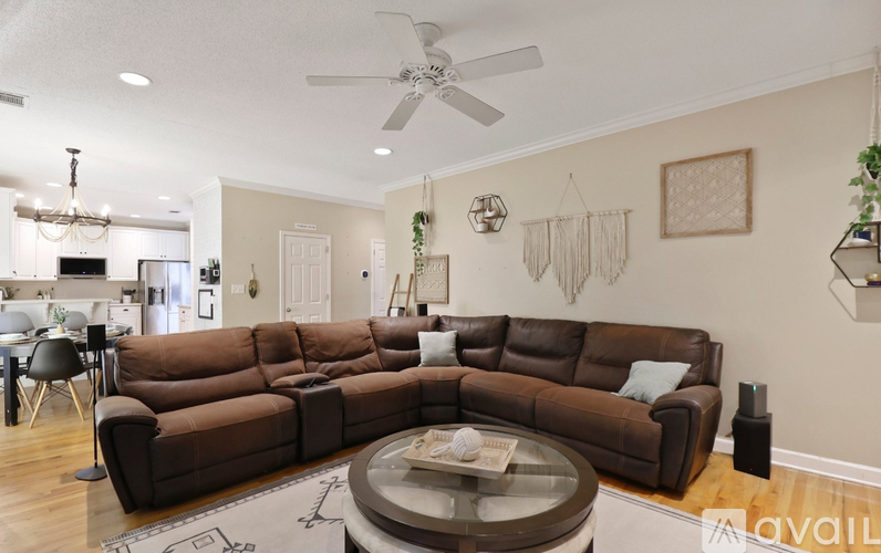 A living room with a brown sectional sofa and a glass coffee table.