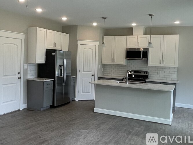 A kitchen with a refrigerator, microwave, and oven.