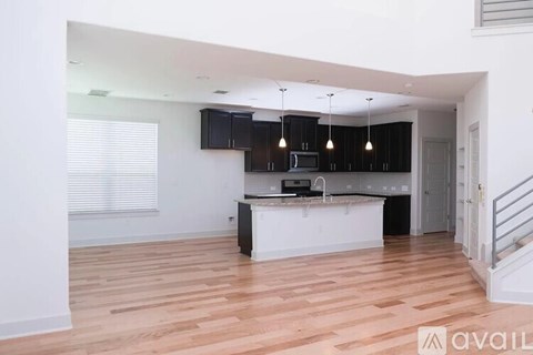 A kitchen with black cabinets and a white island.