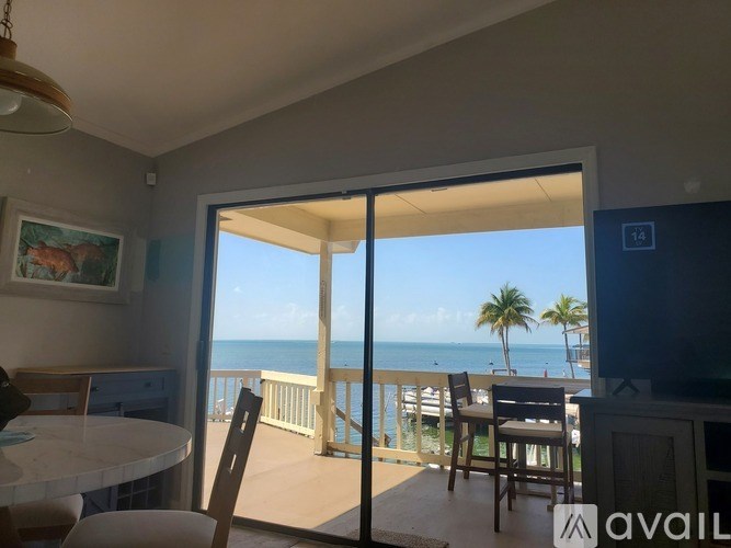 A balcony with a table and chairs overlooking the ocean.