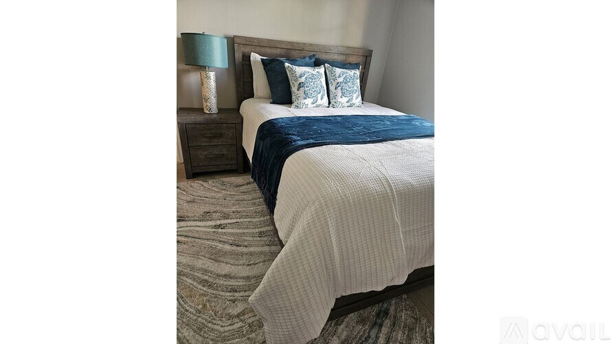A bedroom with a bed, nightstand, and lamp.