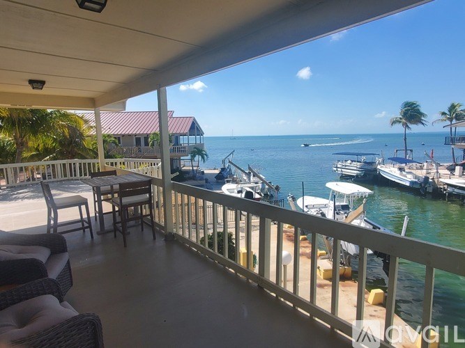 A balcony overlooks a marina with boats and palm trees.