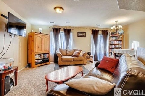 A living room with a brown leather couch and a wooden cabinet.