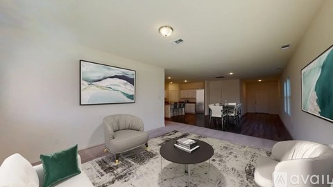 A living room with a white couch, a grey armchair, a black coffee table, and a painting on the wall.