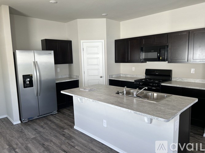 A kitchen with a white island and a stainless steel refrigerator.
