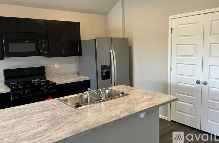 A kitchen with black cabinets and a granite countertop.