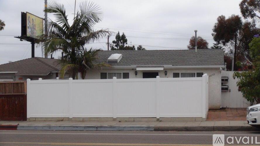 A white house with a white fence and a car parked in front.