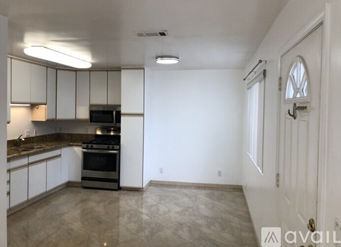 A kitchen with white cabinets and a stainless steel refrigerator.