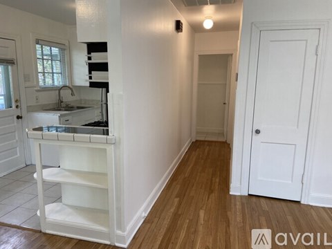 A kitchen with white cabinets and a wooden floor.