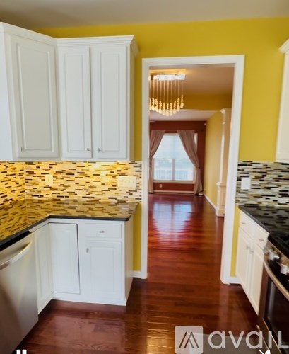 A kitchen with white cabinets and a yellow wall.