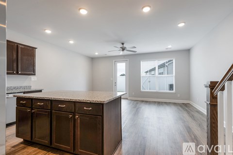 A spacious kitchen with dark brown cabinets and a marble countertop.