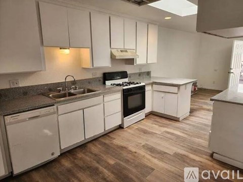 A kitchen with white cabinets and a wooden floor.