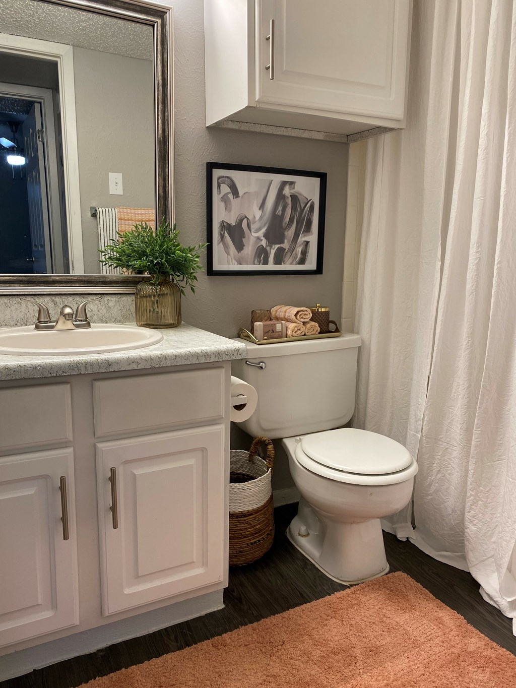 A bathroom with a toilet, sink, and a plant.