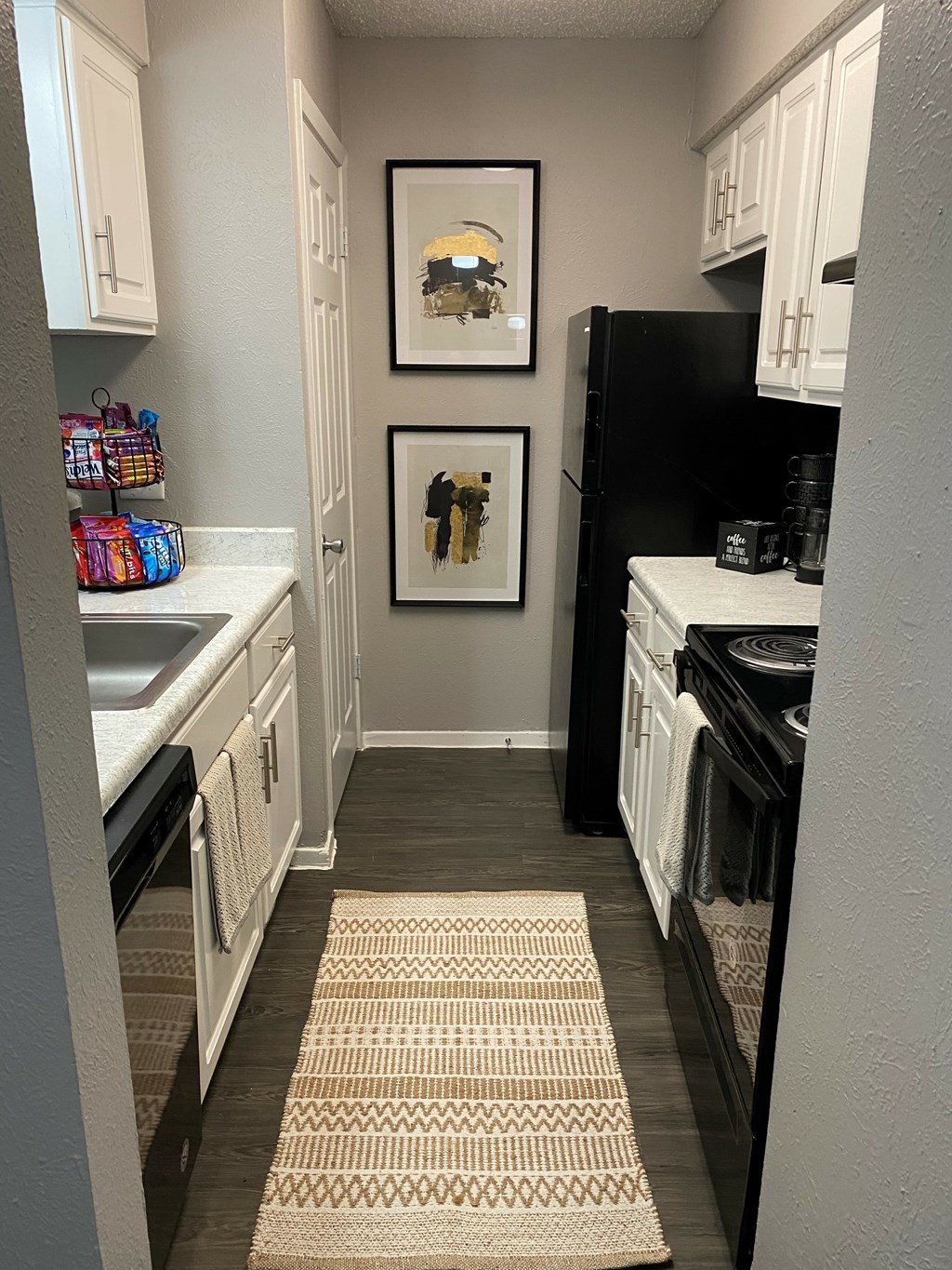 A kitchen with a black fridge and white cabinets.