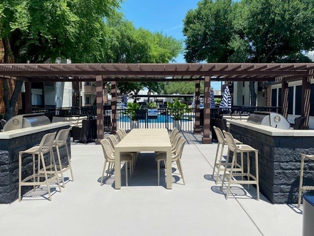A patio with a table and chairs is surrounded by trees.