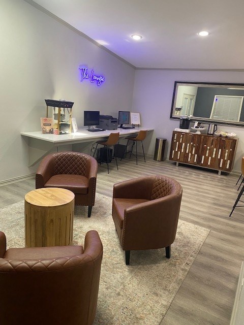 A room with brown leather chairs and a white desk with a computer on it.